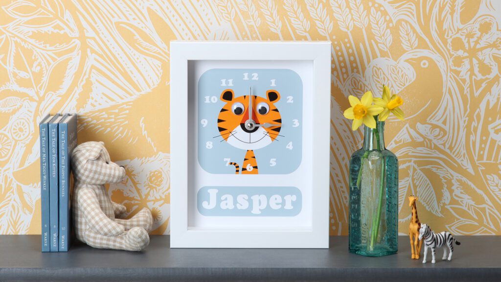 personalised tiger framed clock with googly eyes on a shelf in a child's nursery